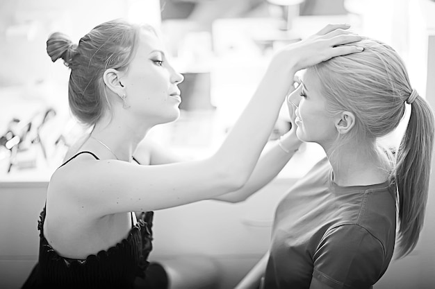 foto antigua en blanco y negro de una chica con maquillaje profesional / maquillaje estricto en la cara de una hermosa modelo profesional en un salón de belleza