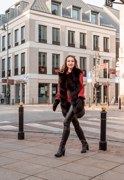 Foto ao ar livre do modelo feminino elegante, andando pela cidade nas férias de inverno.