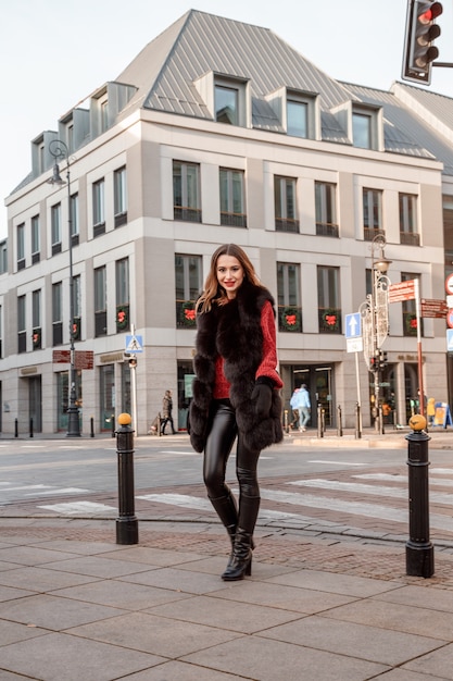 Foto ao ar livre do modelo feminino elegante, andando pela cidade nas férias de inverno.