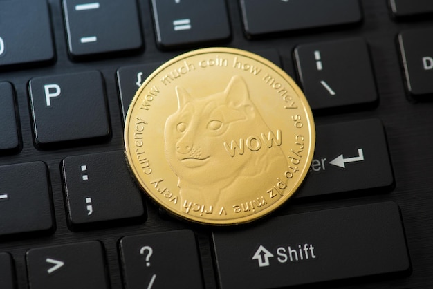 Foto aproximada de moeda de ouro com símbolo dogecoin no fundo do teclado preto