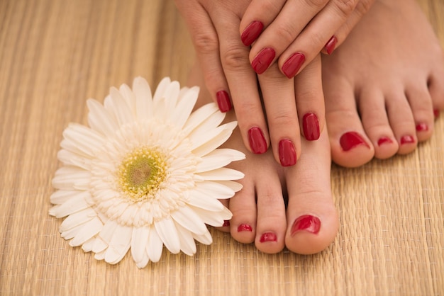 Foto aproximada de pés e mãos femininos no salão spa no procedimento de pedicure e manicure