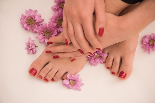 Foto aproximada de pés e mãos femininos no salão spa no procedimento de pedicure e manicure