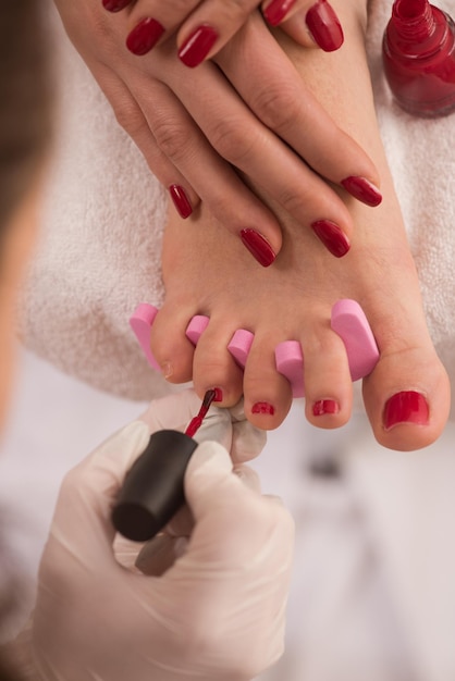 Foto aproximada de pés e mãos femininos no salão spa no procedimento de pedicure e manicure