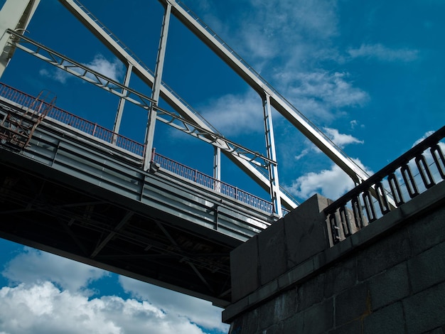 Foto aproximada de uma grande ponte metálica na cidade no fundo do céu