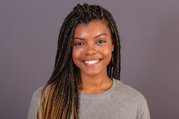 Foto aproximada de uma jovem afro-brasileira mostrando a expressão facial sorrindo feliz alegre