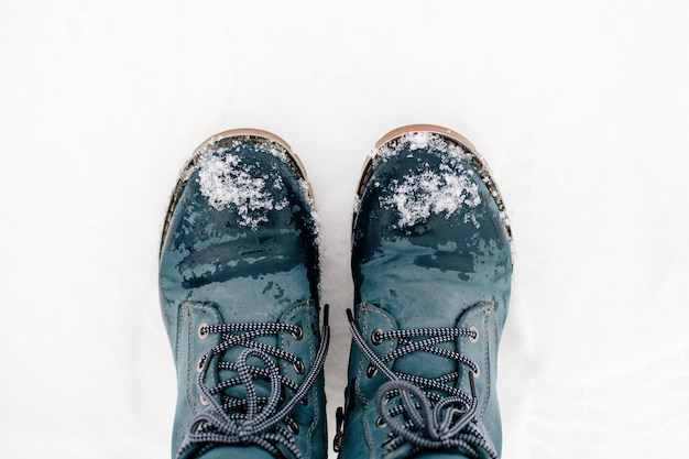 Foto aproximada do inverno colocou simetricamente botas quentes azuis com cadarços na neve fazendo pegada na...