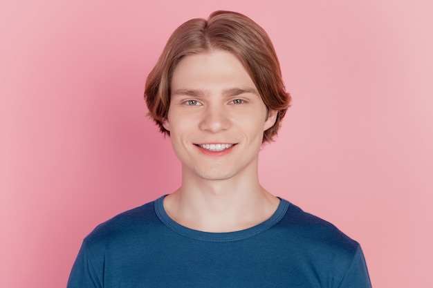 Foto de apuesto joven en ropa casual feliz sonrisa positiva se encuentra en el fondo de la pared rosa