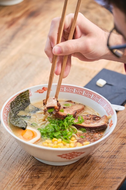 Foto de archivo de una persona no reconocida disfrutando de sopa de fideos en un restaurante japonés.