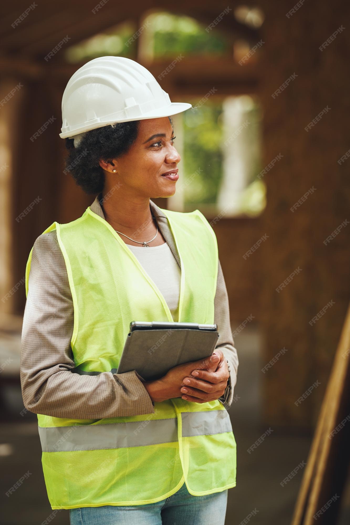 Foto de una arquitecta africana usando una tableta digital y revisando el  sitio de construcción de una nueva casa de madera. lleva ropa de trabajo  protectora y casco blanco. | Foto Premium