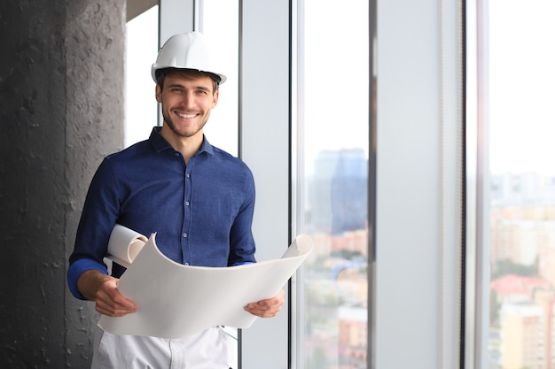 Foto de arquitecto masculino vistiendo casco e inspeccionando el nuevo edificio.