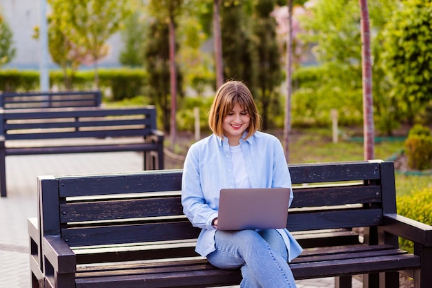 Foto de una atractiva estudiante en el parque navegando en un cuaderno charlando con amigos haciendo tareas domésticas inspiración