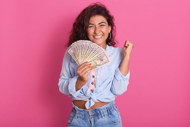 Foto de atractiva joven mujer de pelo ondulado está sonriendo