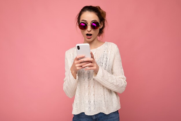 Foto de atractiva mujer joven sorprendida insatisfecha vistiendo casual blusa blanca y gafas de sol coloridas