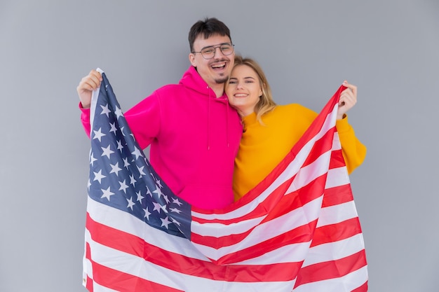 Foto de atractiva pareja multiétnica hombre y mujer envueltos en bandera americana