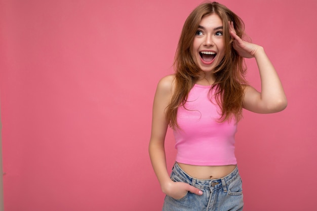 Foto de atractivo lindo feliz sorprendido emocional joven poising aislado en la pared del fondo