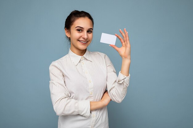 Foto de atractivo positivo sonriente joven morena mujer vistiendo blusa blanca