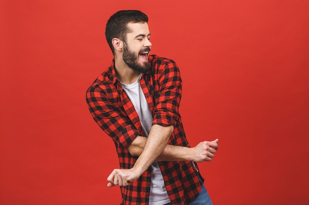 Foto del baile hermoso del hombre joven aislada sobre la pared roja.