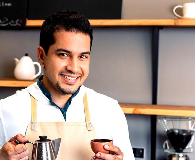 Foto barista sorrindo enquanto segura uma chaleira e uma xícara de café