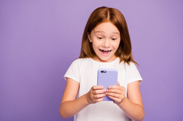 Foto de bastante pequeña niña de jengibre sosteniendo teléfono cara soñadora