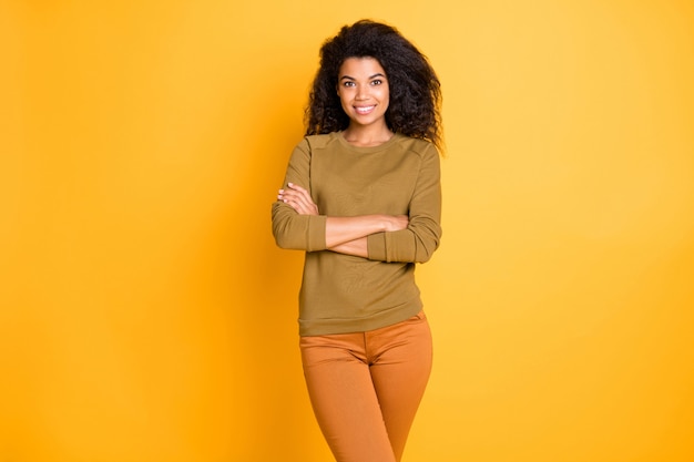 Foto de bastante sorprendente dama de negocios de piel oscura sosteniendo los brazos cruzados estado de ánimo positivo desgaste casual pantalones pullover fondo de color amarillo aislado