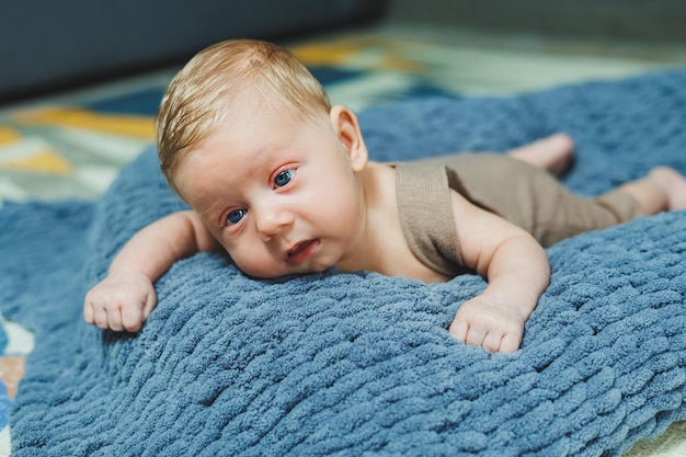 Foto de un bebé en un abrigó de punto Un pequeño niño recién nacido yace sobre una manta de punto gris Retrato de un bebé de un mes de edad