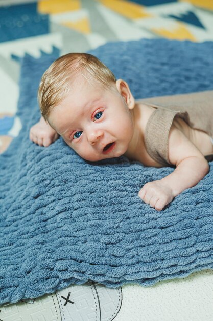 Foto de un bebé en un abrigó de punto Un pequeño niño recién nacido yace sobre una manta de punto gris Retrato de un bebé de un mes de edad