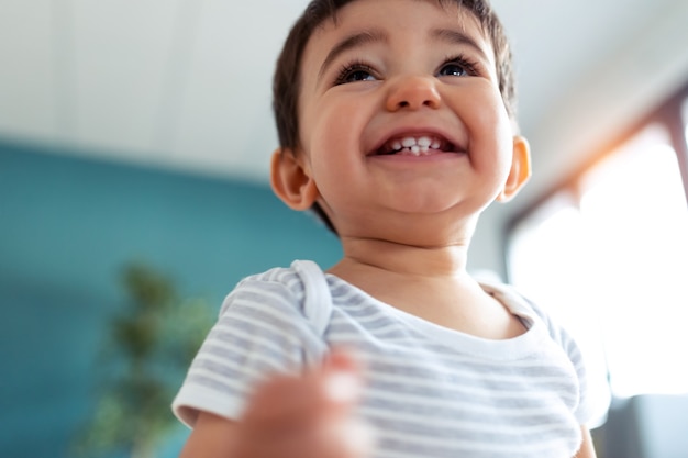 Foto de bebé feliz sonriendo mientras se divierte en casa.