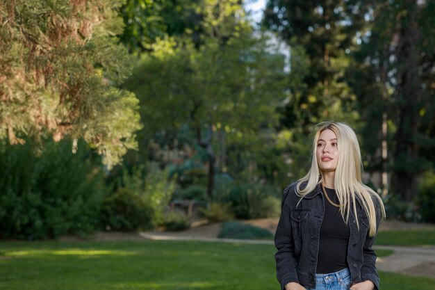 Foto de una bella dama parada en el parque y mirando a un lado