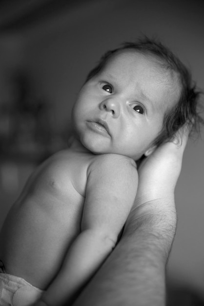 Una foto en blanco y negro de un bebé recién nacido en los brazos de su padre Día del Padre