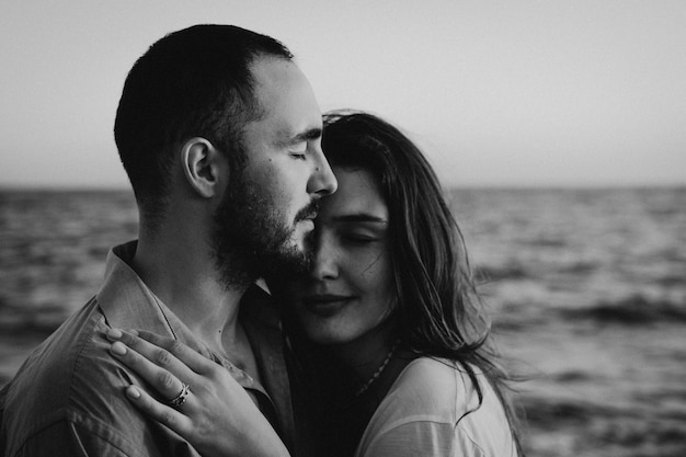 Foto en blanco y negro Joven pareja romántica bailando dando la vuelta por el mar Paisaje marino al atardecer con un hermoso cielo Pareja romántica en la playa al atardecer dorado Pareja amante divirtiéndose en la playa