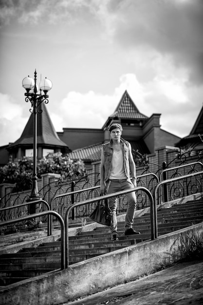 Foto en blanco y negro de un tipo de moda con una bolsa de pie en las escaleras