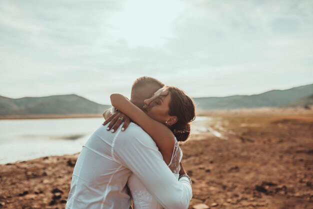Foto de boda. una joven pareja casada divirtiéndose y bailando junto a un gran lago. enfoque selectivo. foto de alta calidad