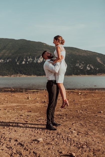 Foto de boda. Una joven pareja casada divirtiéndose y bailando junto a un gran lago. Enfoque selectivo. foto de alta calidad