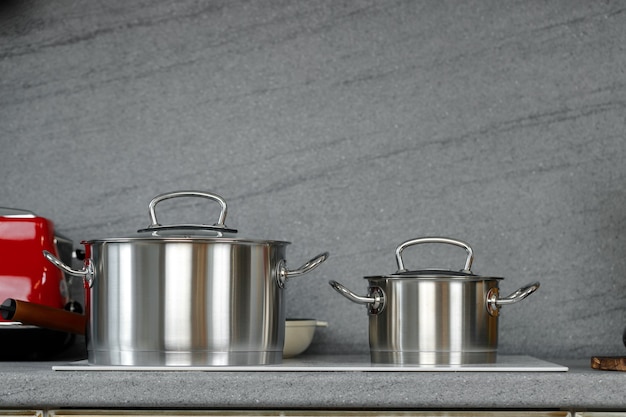 Foto de bodegón de cacerolas de metal en la estufa de inducción en la cocina