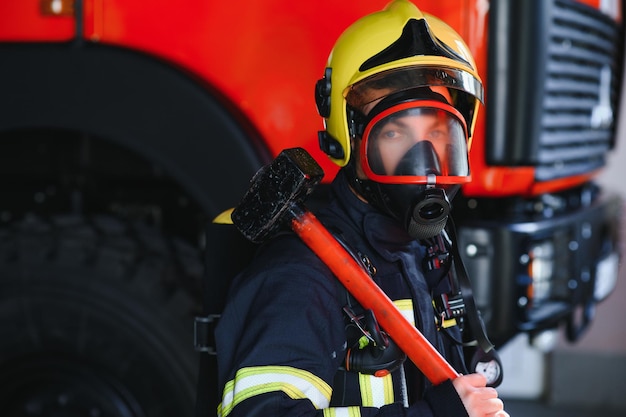 Foto foto de bombero con máscara de gas y casco cerca del camión de bomberos