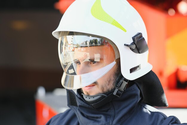 Foto de bombero con máscara de gas y casco cerca del camión de bomberos