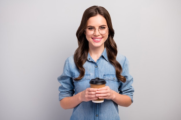 Foto de bonita dama independiente mantenga taza de papel bebida de café caliente tienen un descanso proceso de trabajo especificaciones de desgaste casual jeans camisa de mezclilla color gris aislado