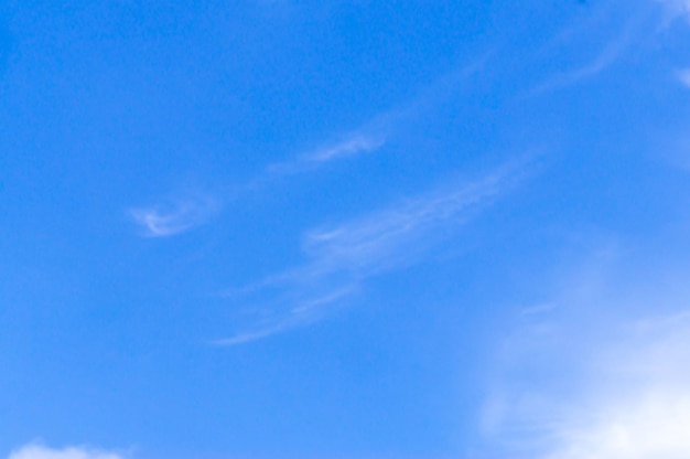 Foto borrosa de la hermosa textura del cielo azul con una pequeña nube blanca extraña y una luz clara bajo el brillo del sol como fondo