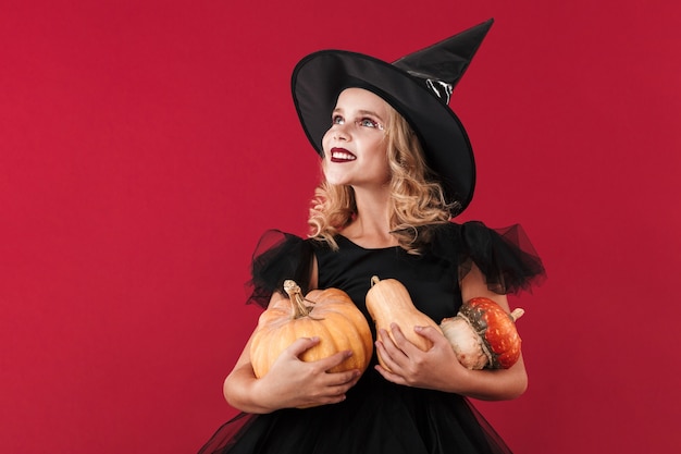 Foto de bruja de niña sonriente optimista positiva en disfraz de halloween de carnaval