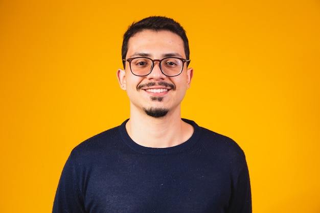 Foto de cabeza de chico con gafas mirando a la cámara con una sonrisa, aislado sobre fondo amarillo