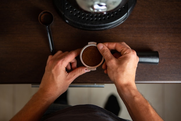 Foto foto de cafetera, mano de hombre vertiendo café en la cocina