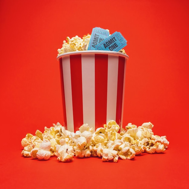 foto de una caja redonda de palomitas de maíz con dos entradas azules sobre un fondo rojo. ideal para diseños de sitios web y revistas
