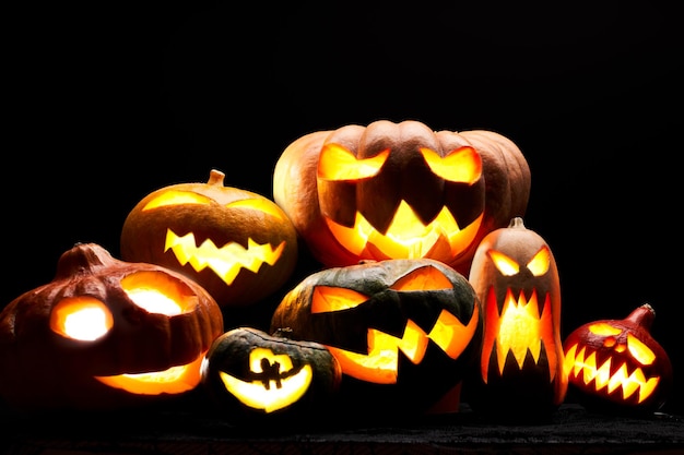 Foto de calabazas de halloween con bocas ardientes sobre fondo negro en blanco