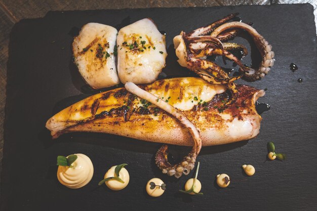 Foto cenital de un plato de calamares en una placa negra.