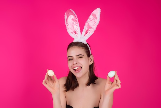 Foto de cerca de una chica bonita que usa orejas de conejo esponjosas de pascua sostienen huevos de pascua aislados en el estudio backgro