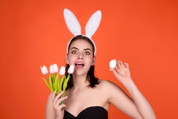 Foto de cerca de una chica bonita que usa orejas de conejo esponjosas de pascua sostienen huevos de pascua aislados en el estudio backgro