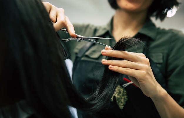 Foto de cerca de una hermosa mujer recibiendo su cabello recortado por un profesional en el salón de belleza.