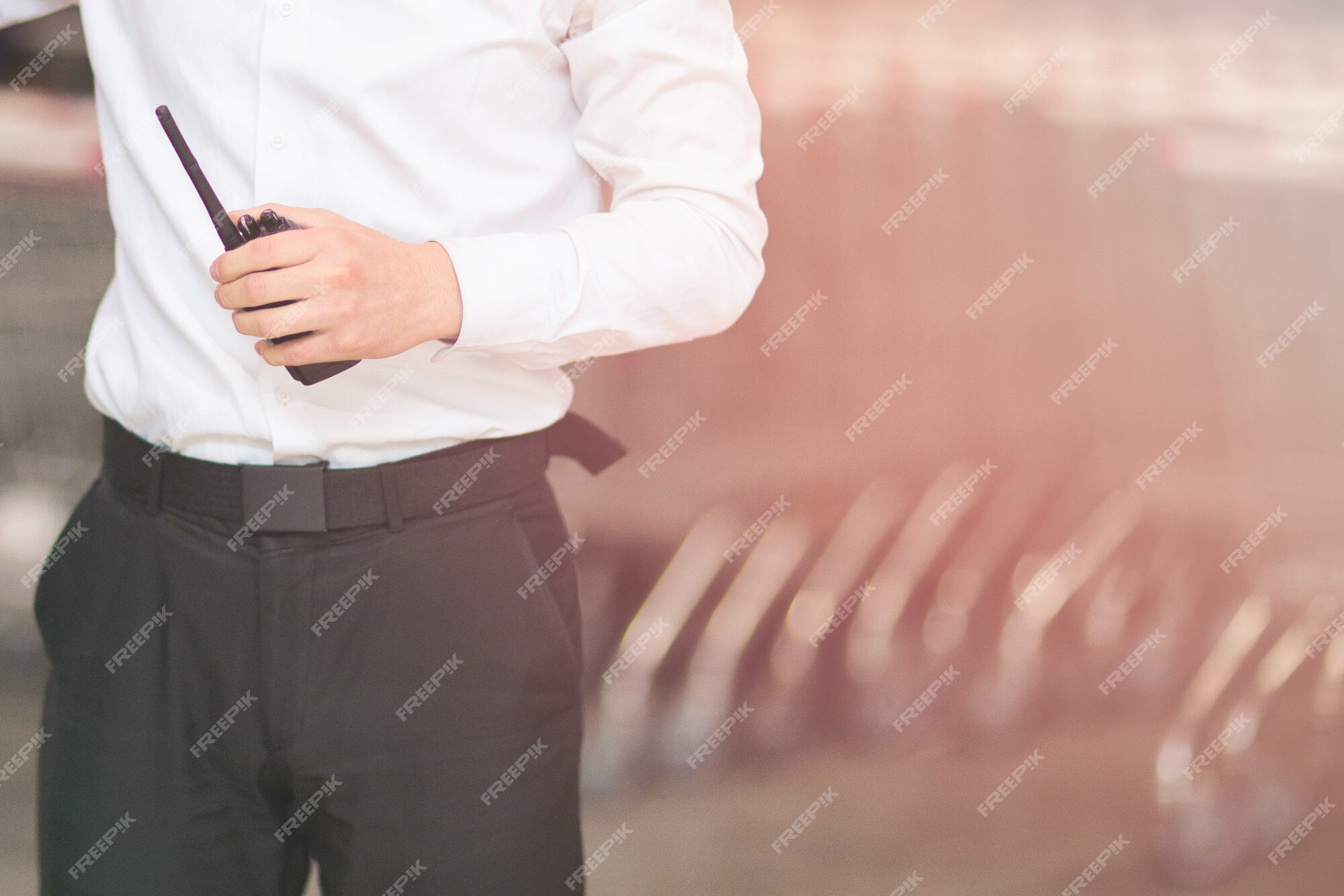 Foto de cerca de un hombre con una blanca y pantalón negro guardia de seguridad sosteniendo un walkie-talkie. | Foto Premium