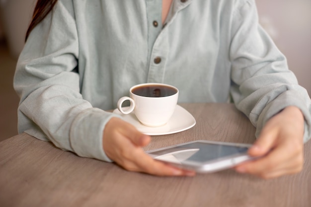 Foto foto de cerca de la tableta con la mujer en ropa casual en casa o en la cafetería y tomando café