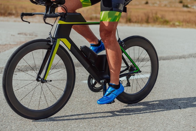 Foto de cerca de un triatleta activo en ropa deportiva y con un casco protector andando en bicicleta. Enfoque selectivo.